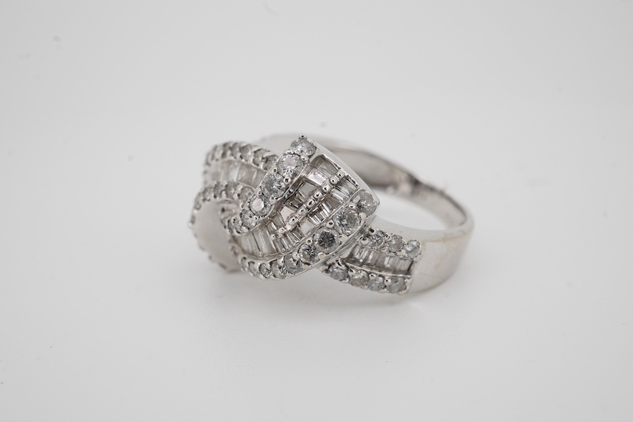 A modern white metal stamped 14k, tapered baguette and round cut diamond cluster set scrolling crossover dress ring, size K, gross weight 5,5 grams. Condition - fair to good